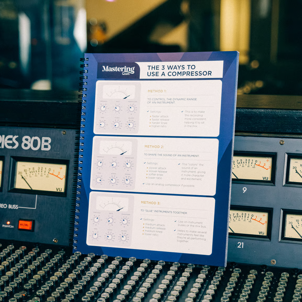 The Mixing & Mastering Cheat Sheet Binder, open on a mixing console